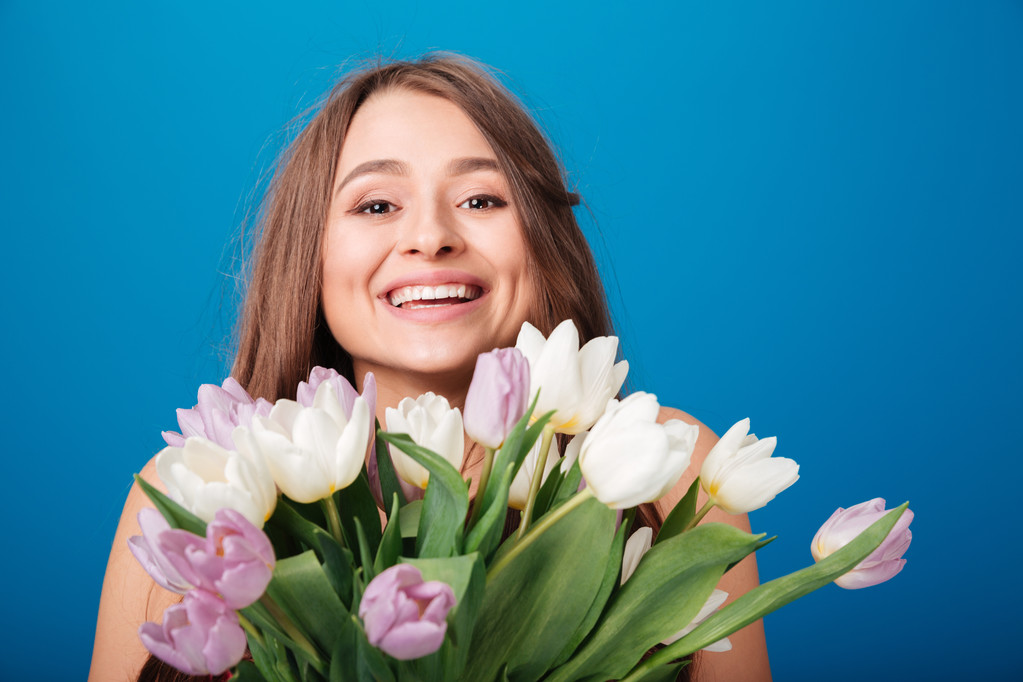 Весела красива жінка посміхається і тримає букет весняних квітів
 - Фото, зображення