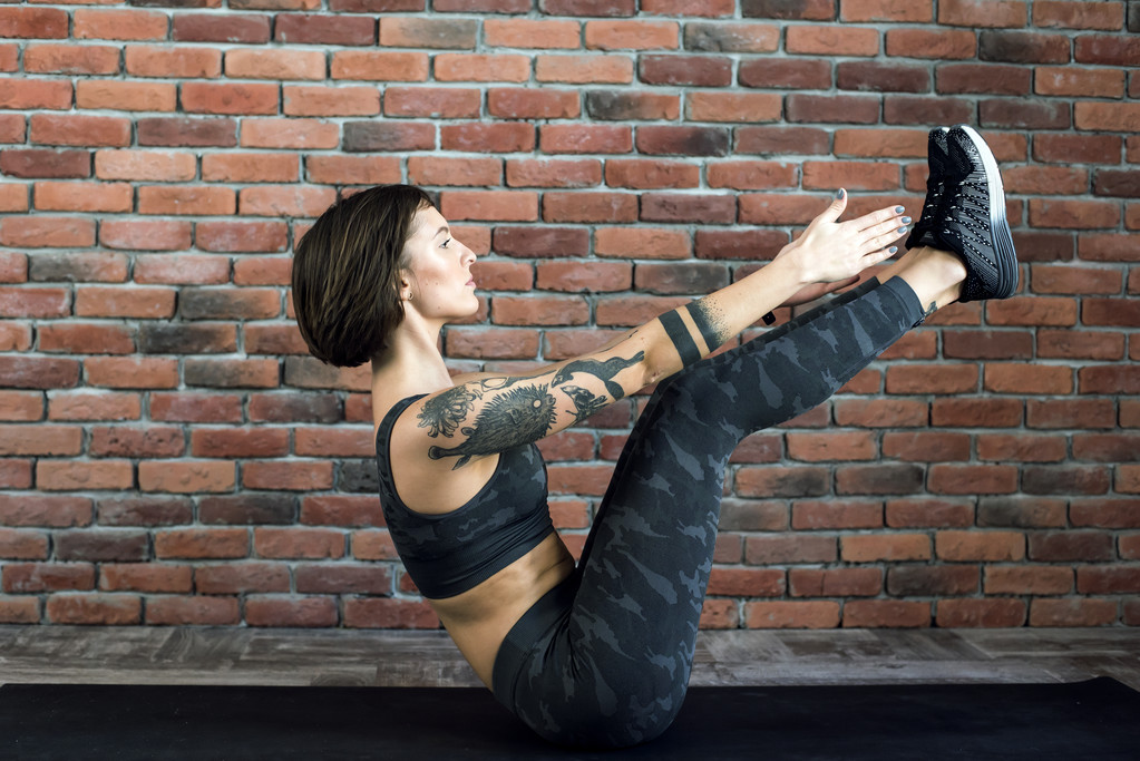 wytatuowany kobieta robi ćwiczenia pomieszczeniu, sportowy kobieta praktykowania jogi - Zdjęcie, obraz