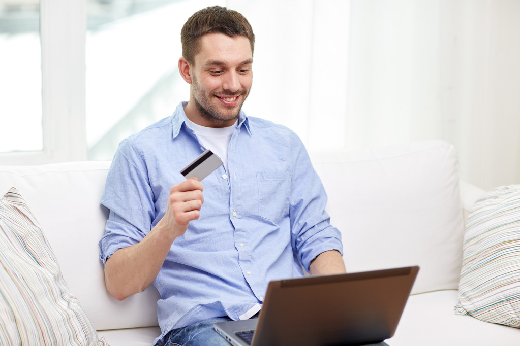 χαμογελαστός άνθρωπος με φορητό υπολογιστή και πιστωτική κάρτα στο σπίτι - Φωτογραφία, εικόνα