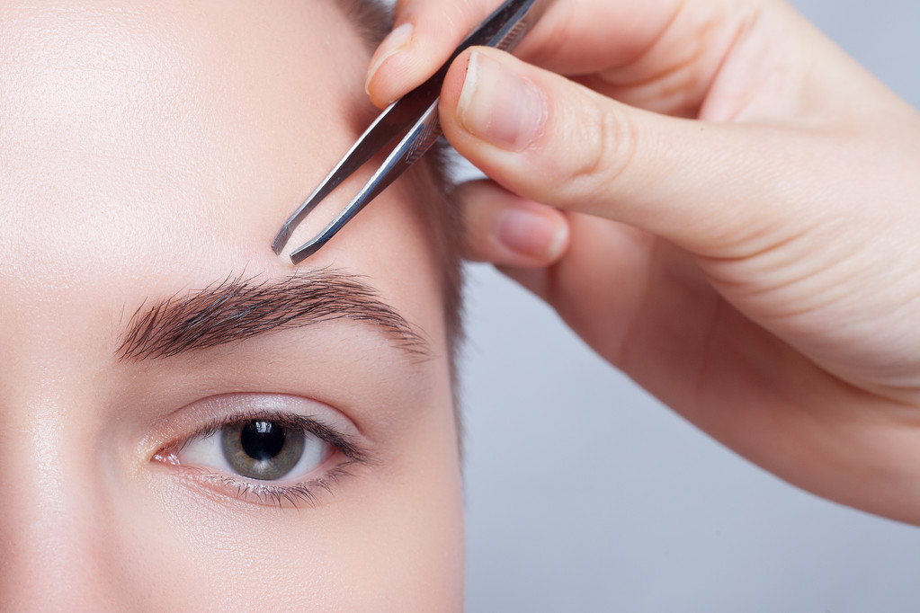 junge Frau mit kurzen Haaren zupft Augenbrauen Pinzette aus nächster Nähe - Foto, Bild