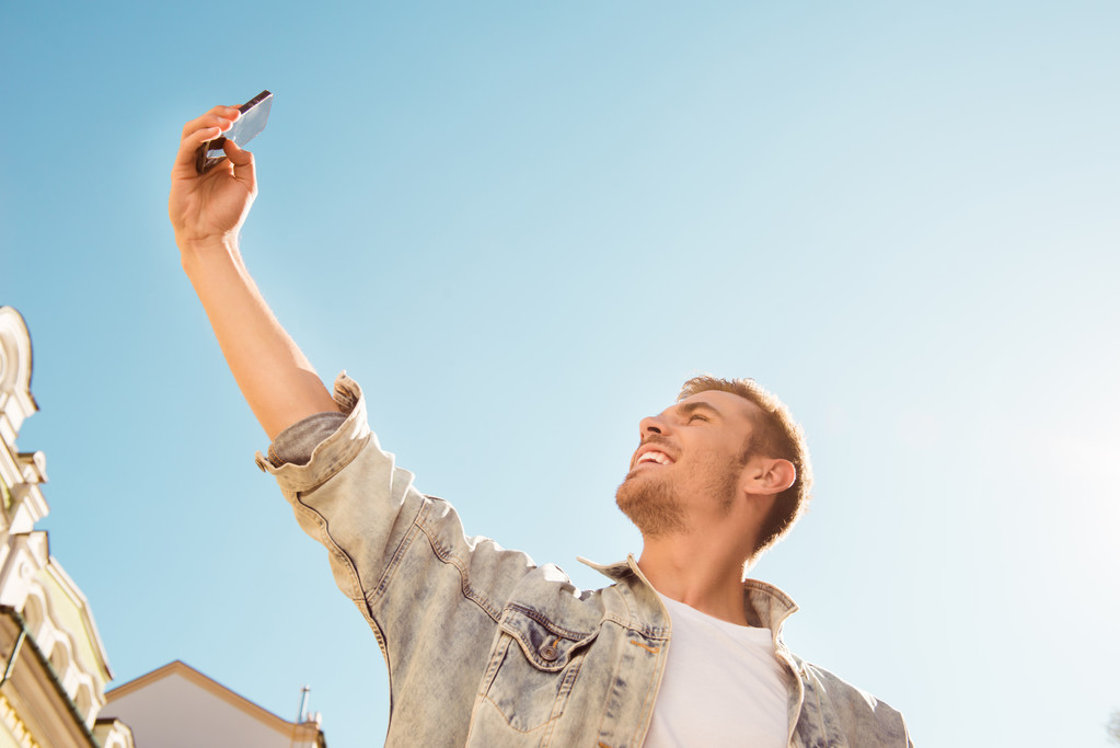 Aantrekkelijke jonge man selfie maken op de achtergrond van de hemel - Foto, afbeelding