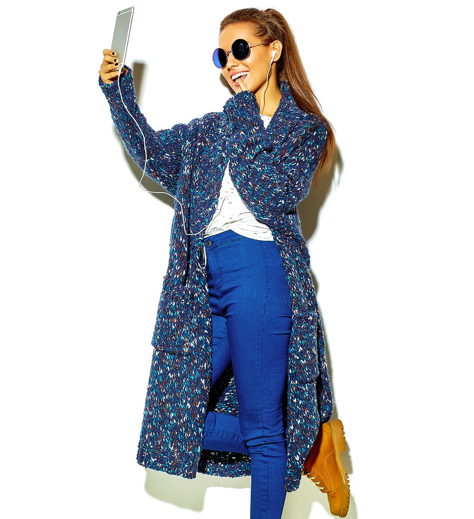 Porträt der schönen fröhlich lächelnde brünette Frau Mädchen in lässiger blauer Hipster-Sommerkleidung ohne Make-up isoliert auf weiß in Sonnenbrille Musik hören in Smartphone mit Kopfhörern und Selfie machen - Foto, Bild
