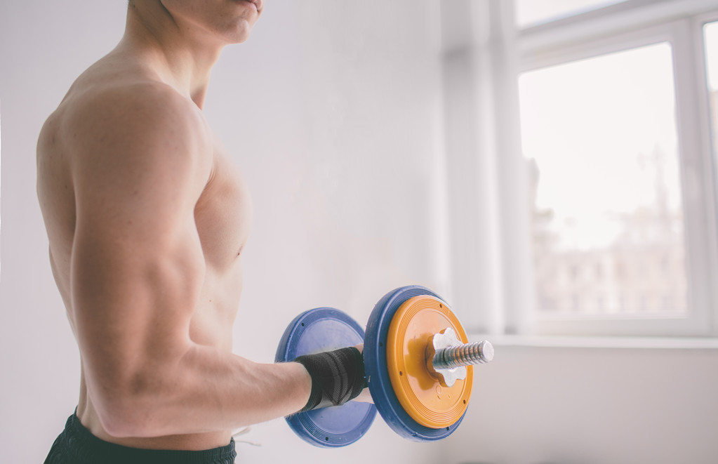Man with muscular torso.  Closeup of a muscular young man lifting weights - Photo, Image