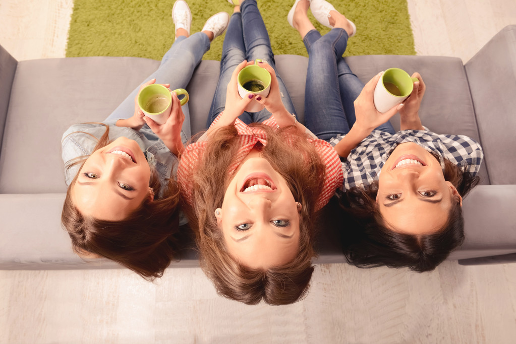 Foto van het bovenaanzicht van vrolijke meisjes zitten op de Bank met cups - Foto, afbeelding