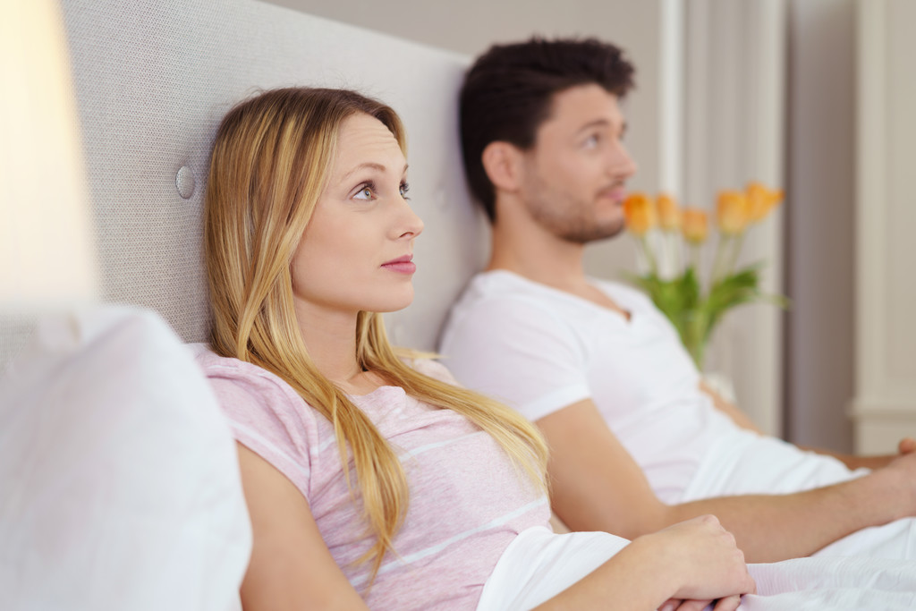 Jovem casal sentado na cama assistindo televisão
 - Foto, Imagem