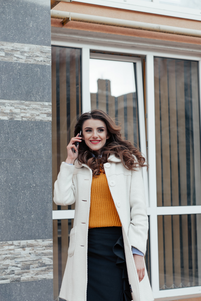 Beautiful girl with a phone in town - Photo, Image