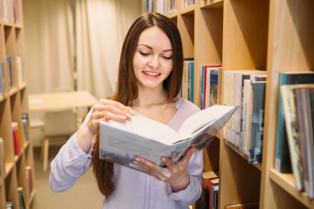 Opiskelija tyttö opiskelee kirjastossa
 - Valokuva, kuva
