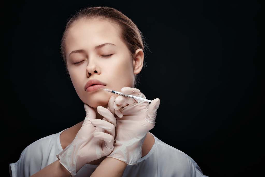 Porträt einer jungen Kaukasierin, die eine kosmetische Injektion bekommt - Foto, Bild