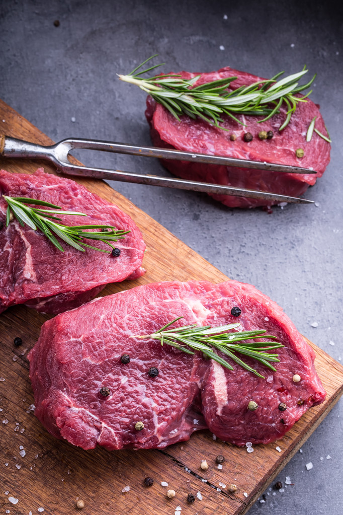 Steak. rohes Rindersteak. frisches Roh-Roastbeef-Steak in Scheiben geschnitten o Kräuter - Rosmarin Dekoration - Foto, Bild