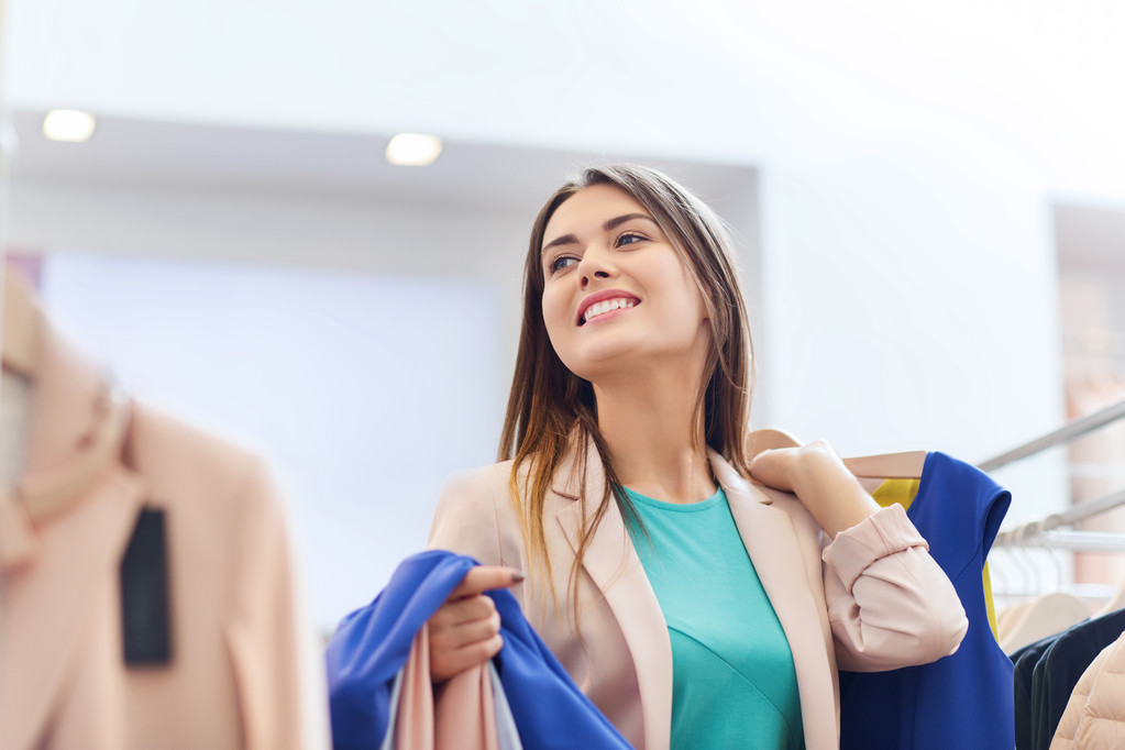 щаслива молода жінка вибирає одяг у торговому центрі
 - Фото, зображення