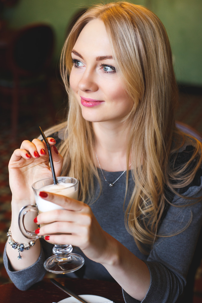 Bella bionda giovane donna in un caffè con una tazza di latte macchiato
 - Foto, immagini