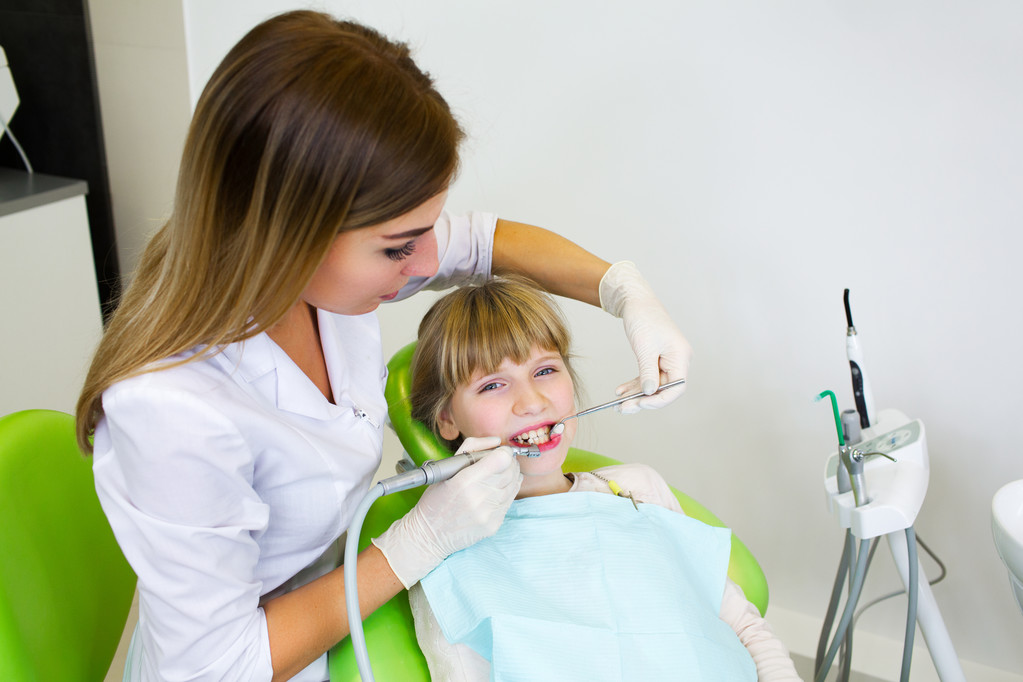 Young handsome dentist treats tooth child, a woman dentist - 写真・画像