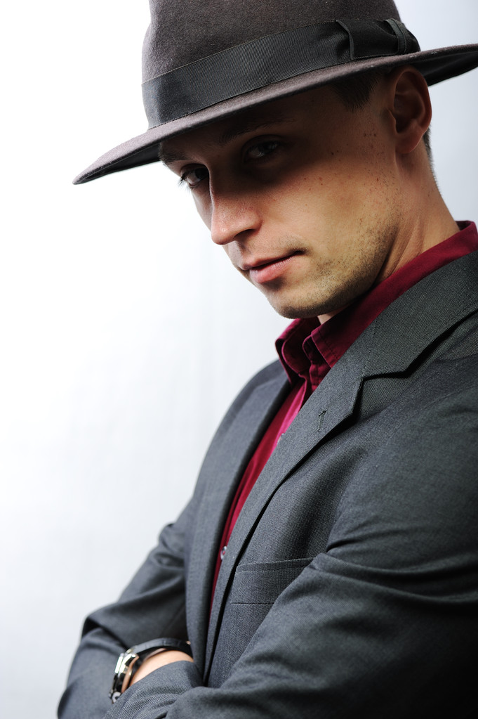 eleganter junger Mann mit Hut blickt in die Kamera - Foto, Bild