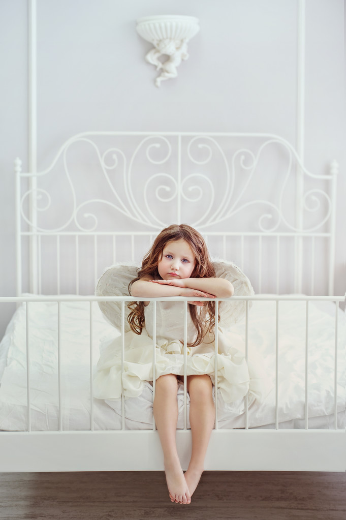 Kislány angyal szárnya a fehér ágy. - Fotó, kép
