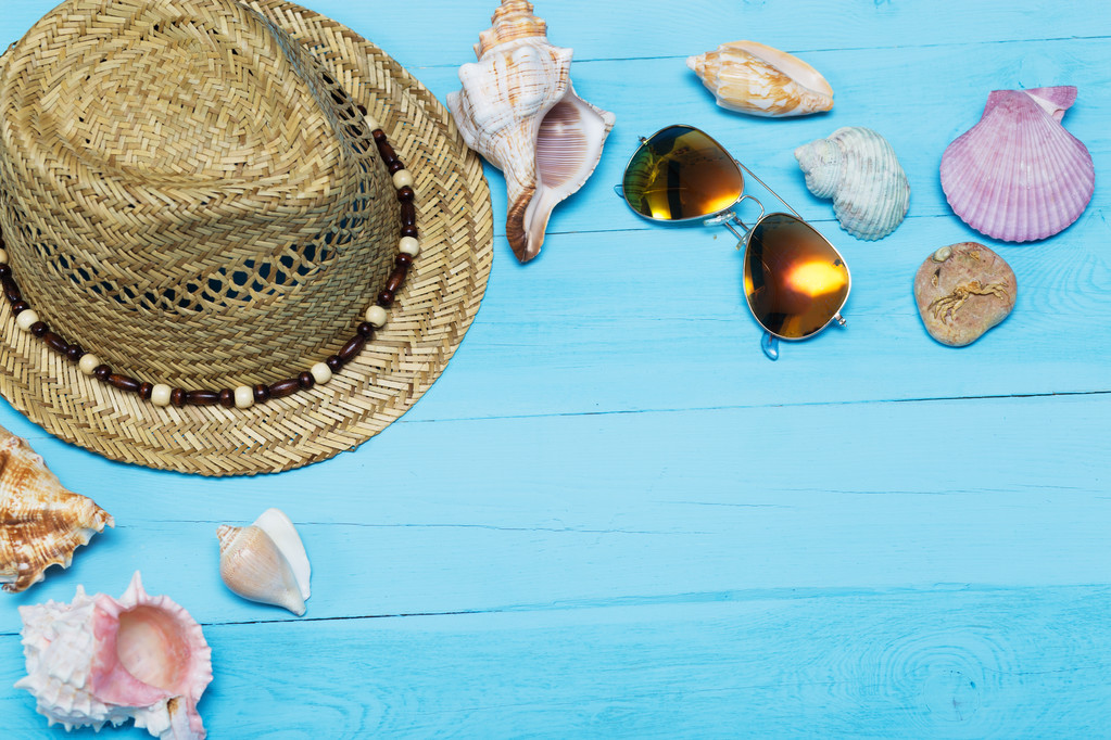 Conchas de mar, sombrero y gafas de sol sobre fondo de madera azul
 - Foto, imagen