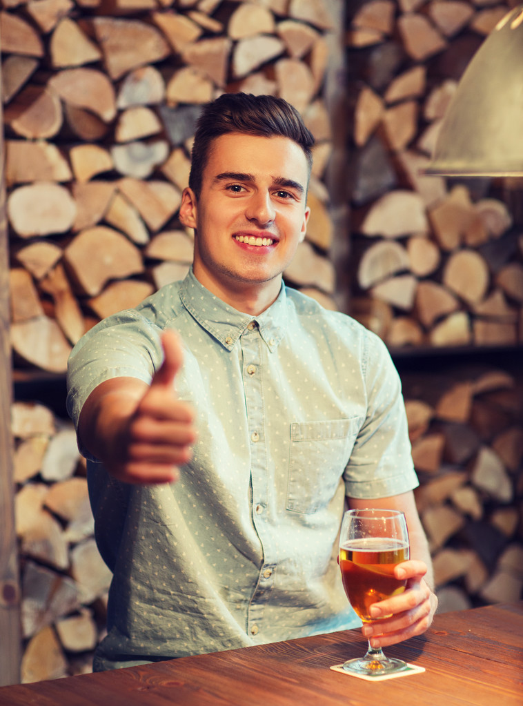 onnellinen mies oluen kanssa näyttää peukalot baarissa
 - Valokuva, kuva