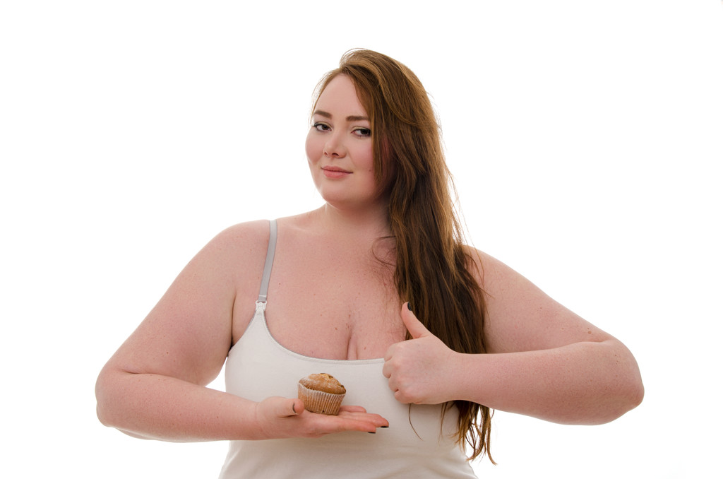 Egy kövér nő egy muffin a kezében elszigetelt fehér background - Fotó, kép