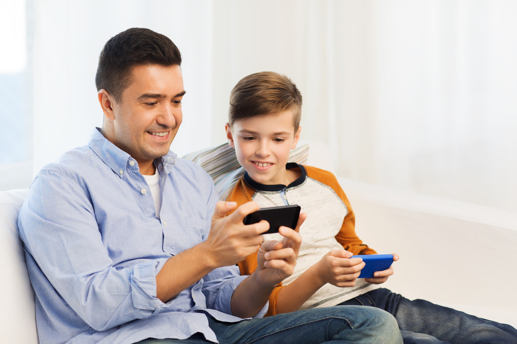 счастливый отец и сын со смартфонами дома
 - Фото, изображение