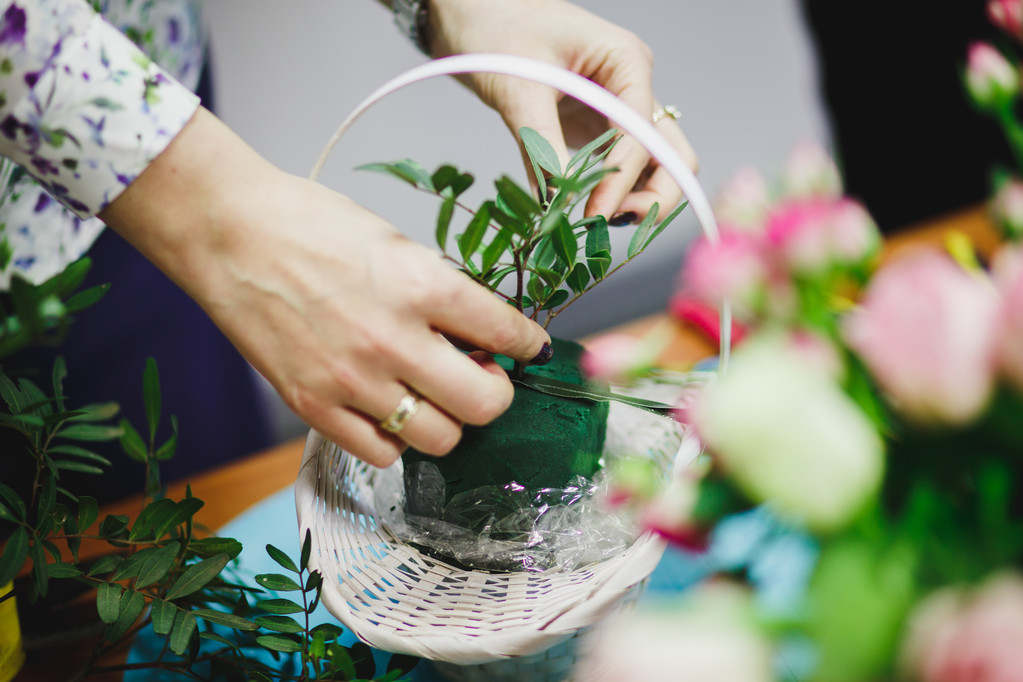 Laboratorio floreale - fiorista fa un mazzo in un cesto. Gli studenti fioristi lavorano insieme
. - Foto, immagini