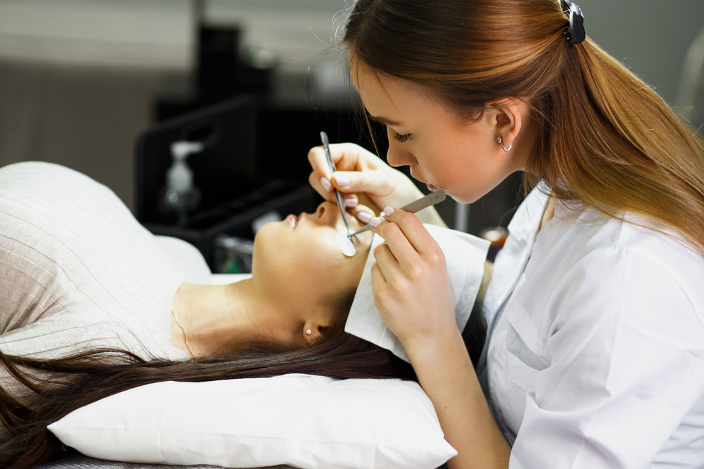 eyelash extension procedure - master and a client in a beauty salon - Photo, Image