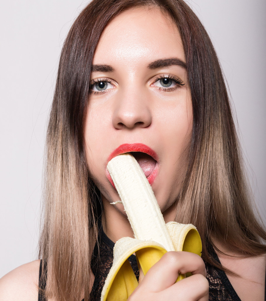 Jeune femme étonnée en lingerie dentelle tenant une banane, elle va manger une banane. elle suce une banane
 - Photo, image