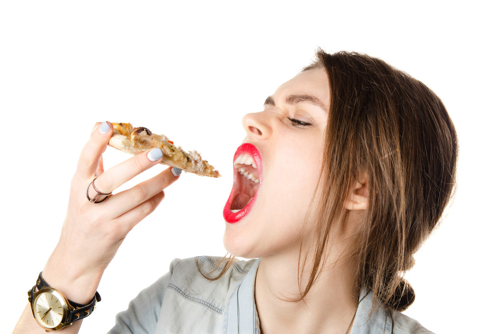 Bastante joven sexy mujer comiendo gran rebanada de pizza con la boca abierta grande de pie sobre fondo blanco
 - Foto, Imagen