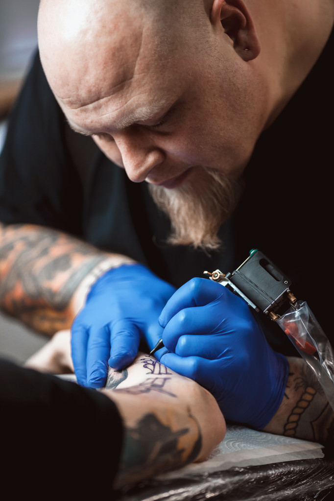 Master tatoeëerder maakt een tattoo op de huid  - Foto, afbeelding