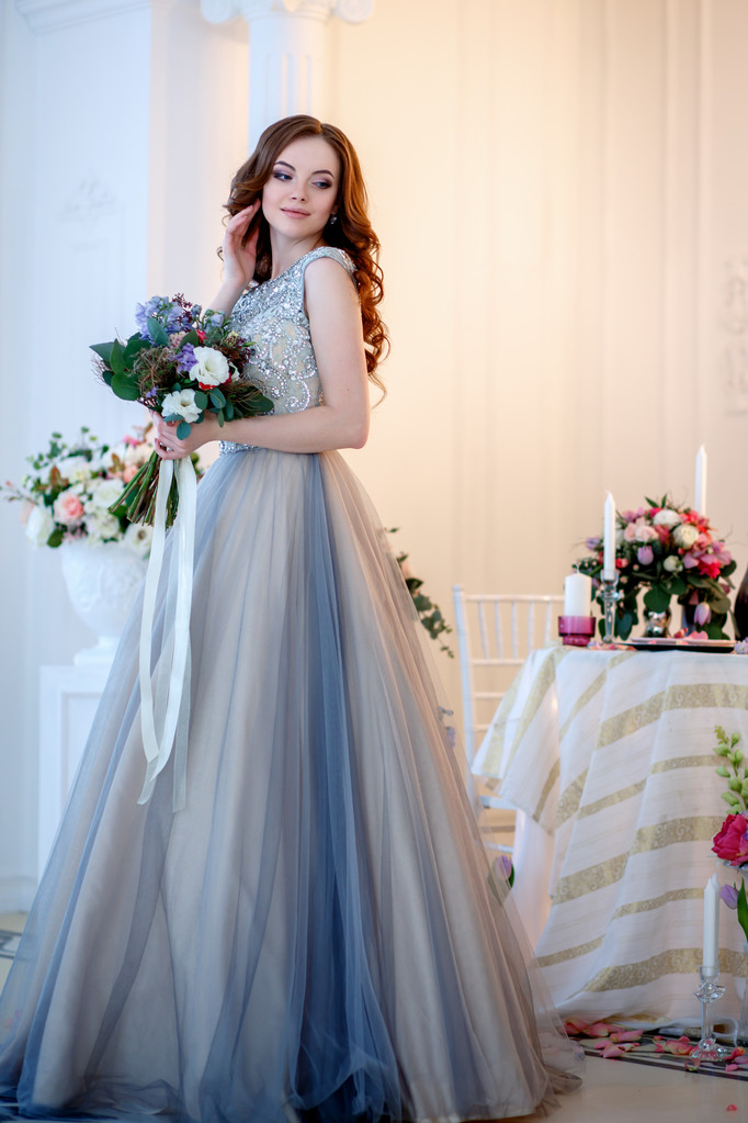 Belle jeune femme dans une robe de luxe à l'intérieur élégant avec un bouquet de fleurs
 - Photo, image