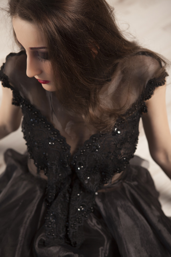 床に横になって黒のドレスで美しい若いブルネットの女性王女の肖像  - 写真・画像