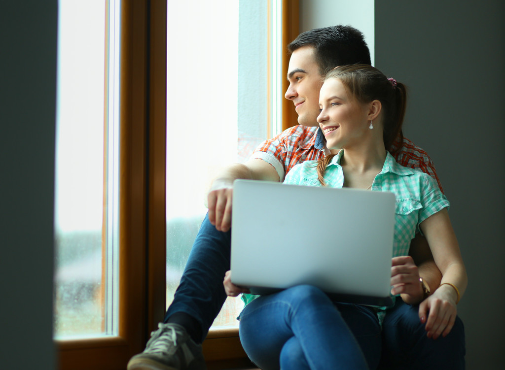 Portrait of young couple moving in new home sitting with laptop - Photo, Image