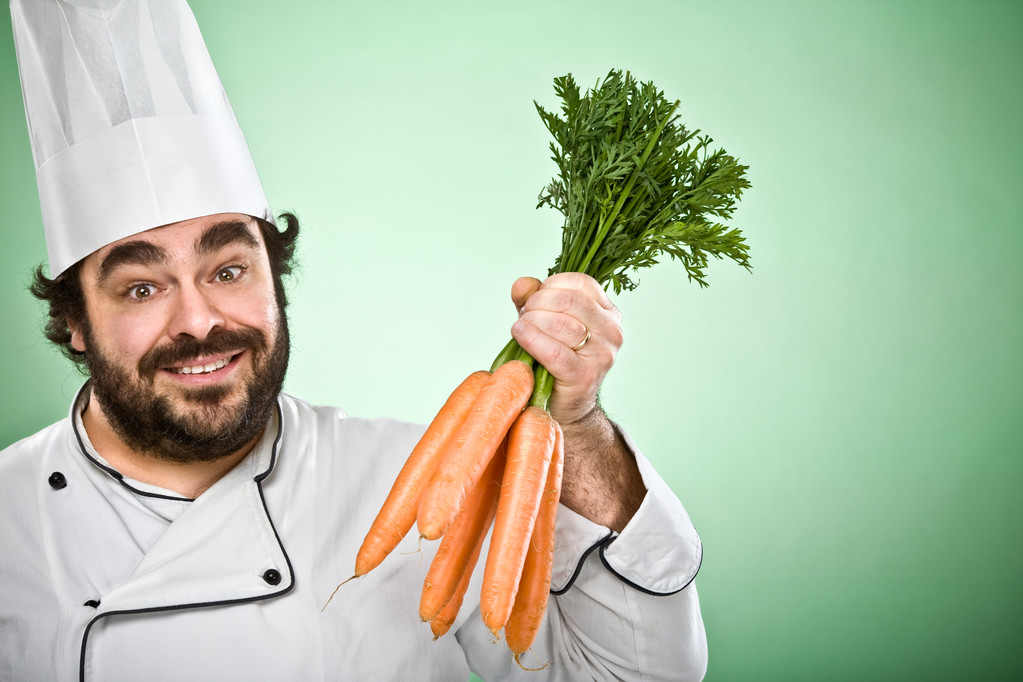 Gelukkig ontspannen chef-kok koken wortelen geïsoleerd op groen - Foto, afbeelding