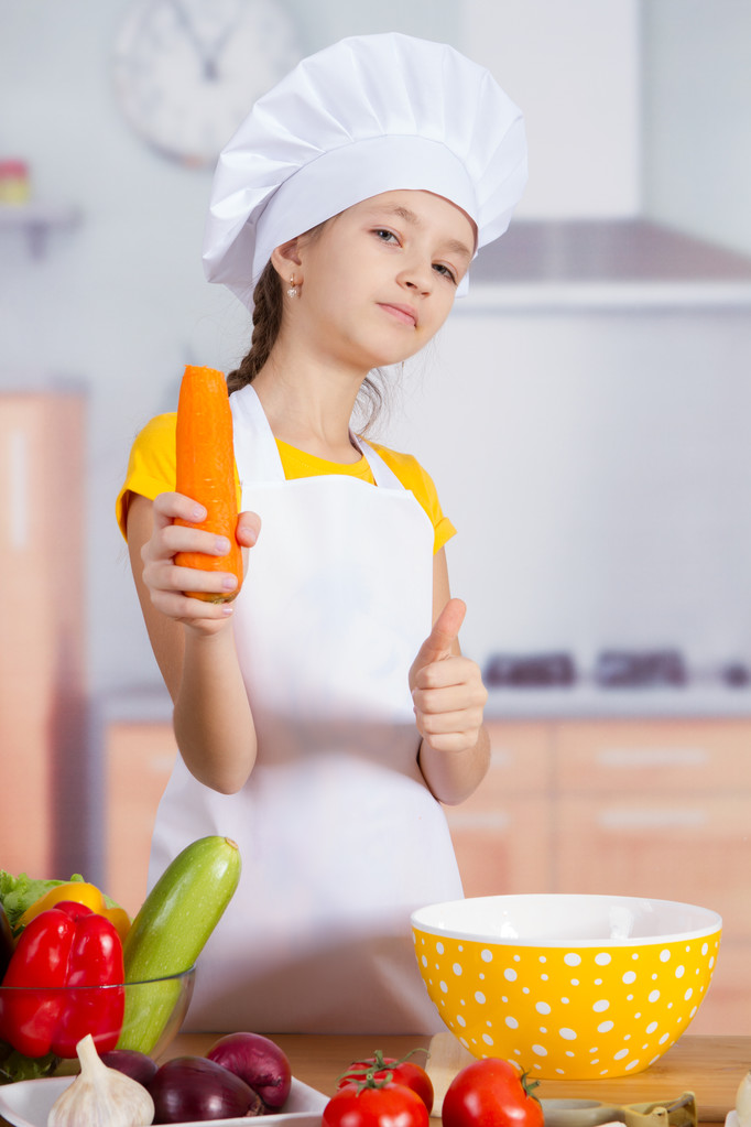 girl chef shows a carrot, thumb up - Photo, Image