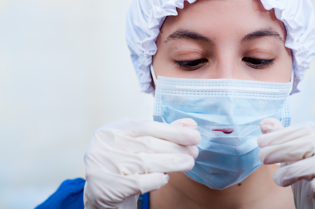 Closeup headshot enfermeira vestindo tampão bouffant e máscara facial segurando amostra de sangue em vidro deslizante para câmera
 - Foto, Imagem