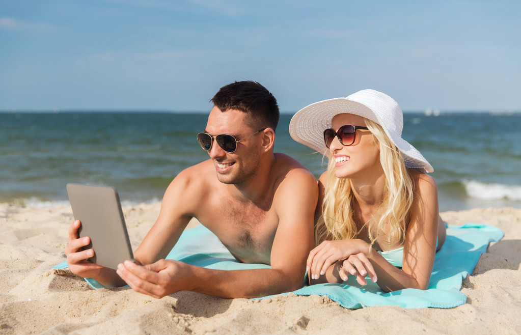 タブレット pc は、ビーチで日光浴と幸せなカップル - 写真・画像