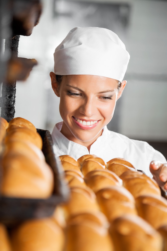 Пекарь смотрит на свежий хлеб в пекарне
 - Фото, изображение