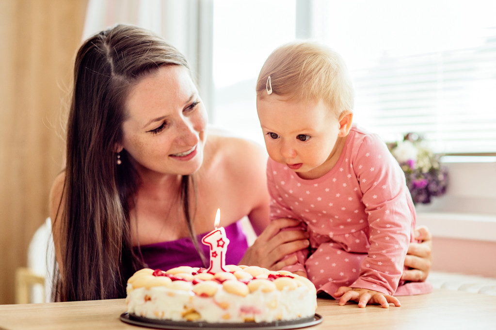 Mutter hält ihre kleine Tochter mit Geburtstagstorte - Foto, Bild