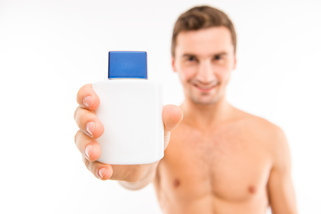 Handsome man showing a lotion after shave, focus on lotion - Photo, Image