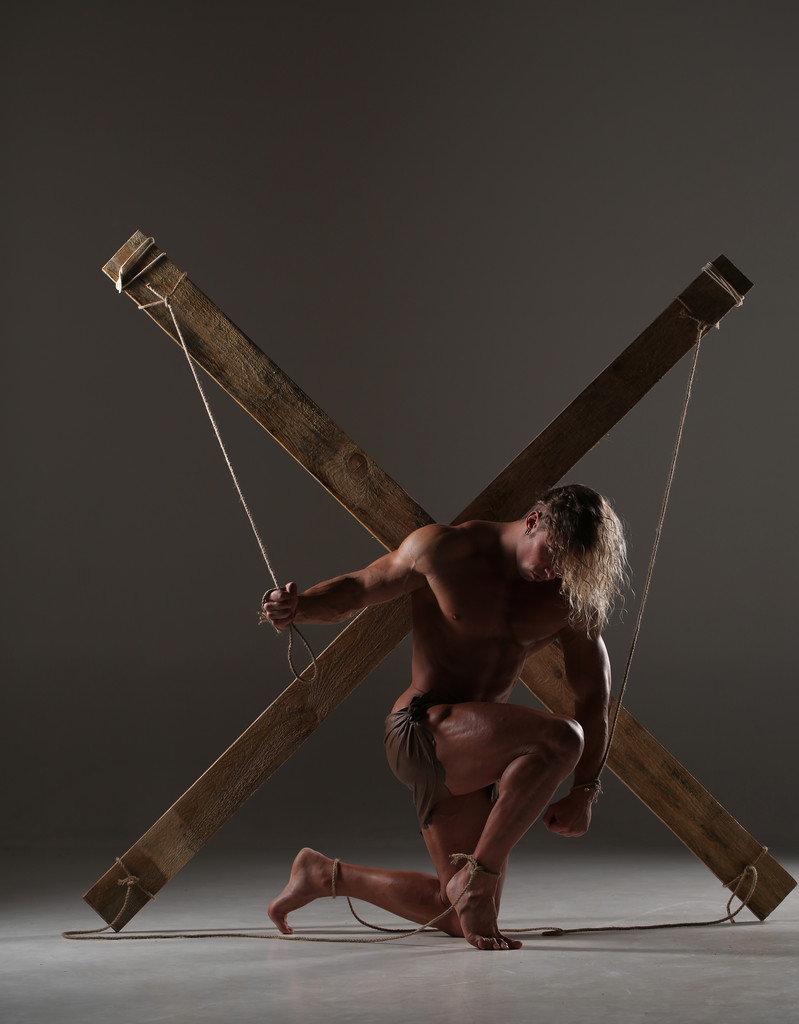 Seksuele naakte man, gespierd, handen gebonden touw op houten balken - Foto, afbeelding