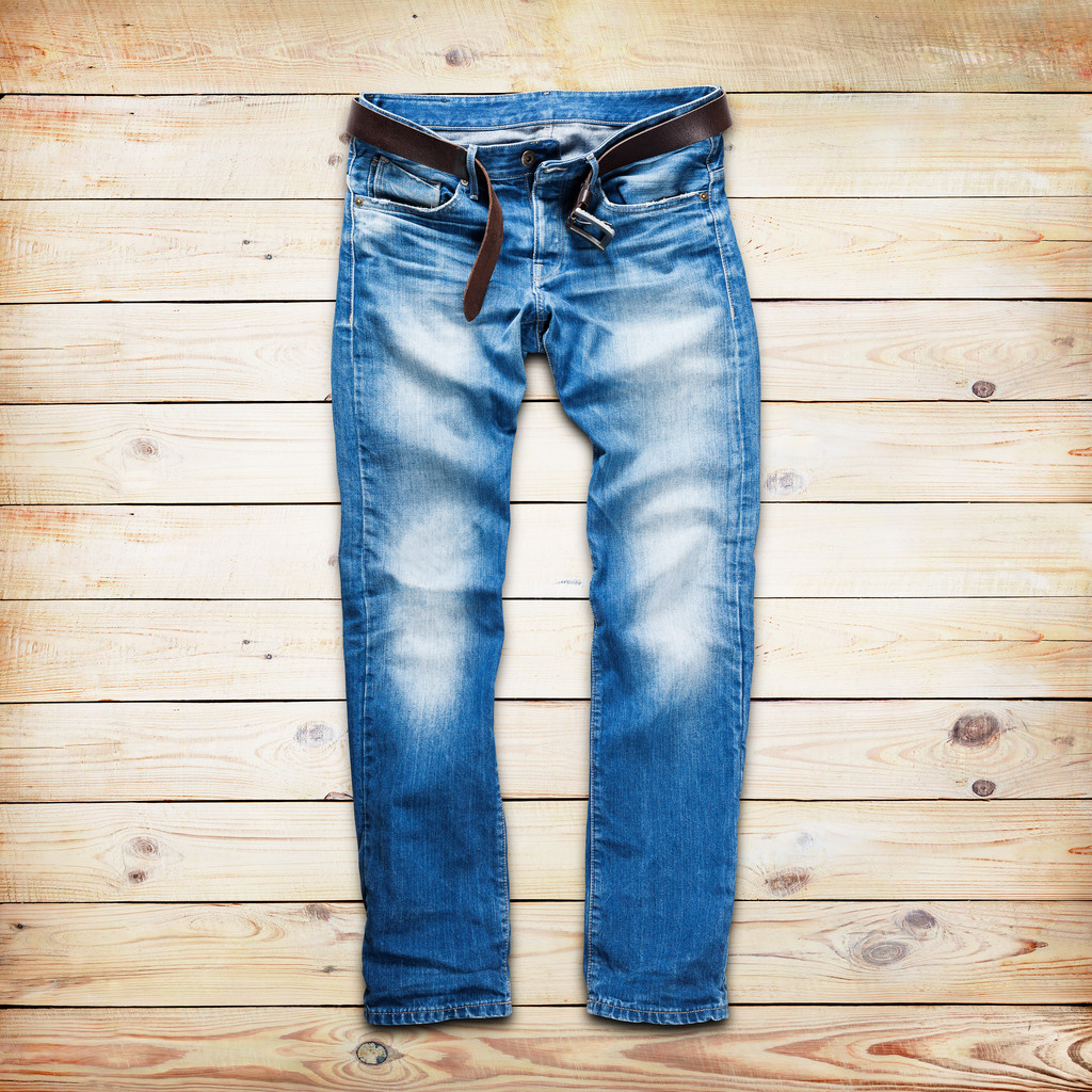 Calça jeans azul com cinto de couro sobre pranchas de madeira branca fundo
 - Foto, Imagem