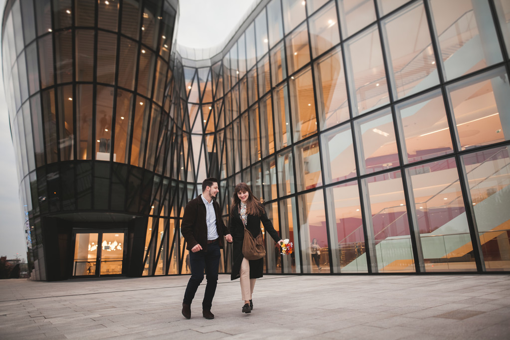 Elegante pareja amorosa caminando y corriendo cerca de un edificio moderno
 - Foto, Imagen