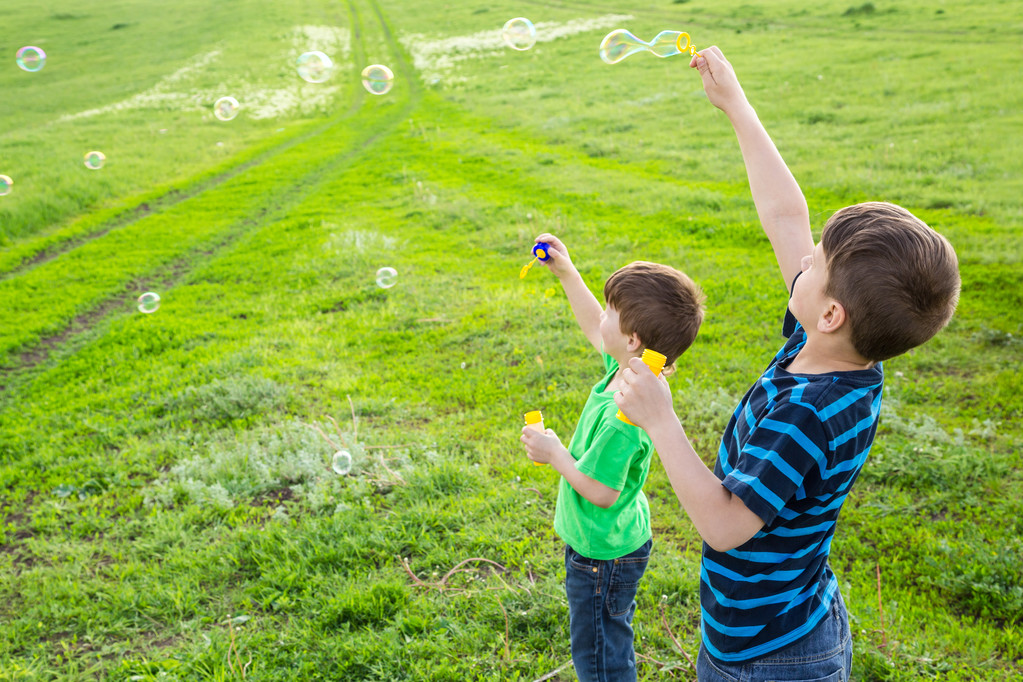 Twee jongens opblazen van de zeepbellen op gazon - Foto, afbeelding
