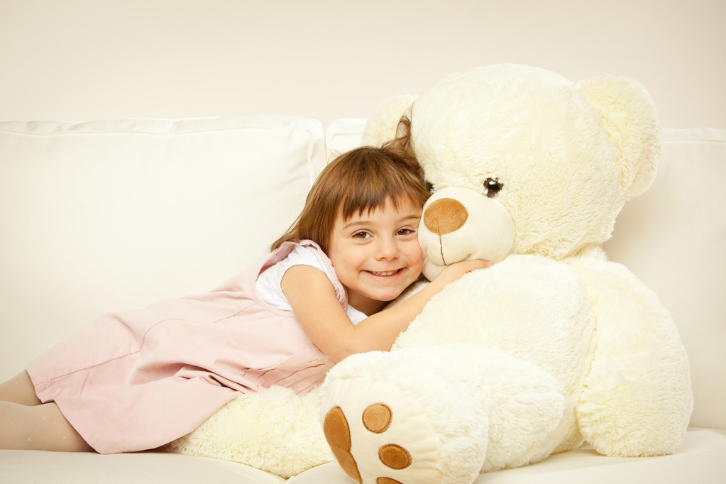 ξανθιά γυναίκες με παιδιά που παίζουν με το λευκό αρκουδάκι σε ένα κρεβάτι - Φωτογραφία, εικόνα