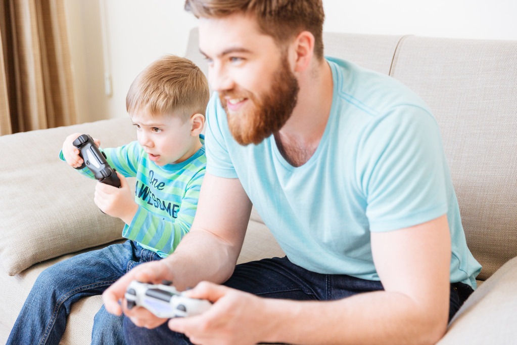 Niño jugando videojuegos con papá sentado en el sofá
  - Foto, imagen