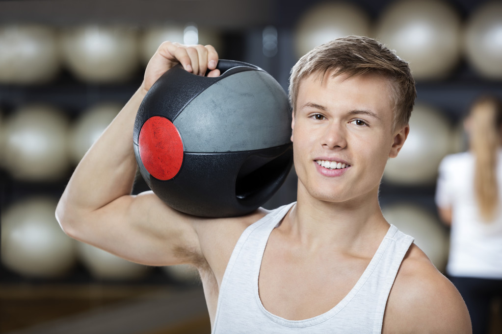 Hombre manteniendo la bola de la medicina en el hombro en el gimnasio
 - Foto, imagen