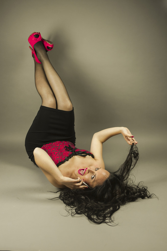 Sonriente hermosa mujer con corsé rojo tumbado con los pies en alto
 - Foto, Imagen