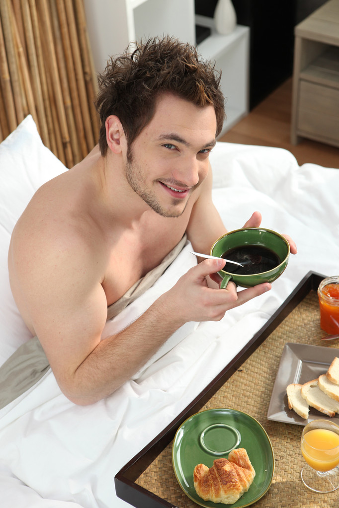 ベッドで朝食をとる男 - 写真・画像