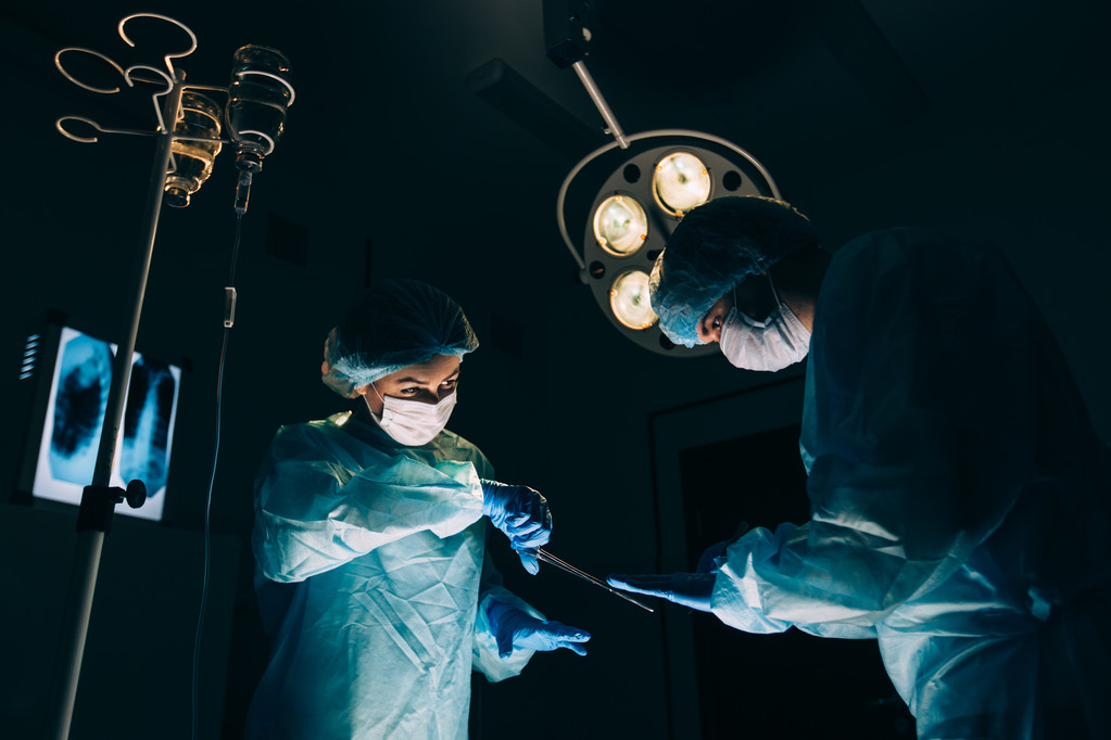 Zespół chirurgów pracujących z monitoringu pacjenta w chirurgiczne sali operacyjnej. Powiększanie piersi - Zdjęcie, obraz
