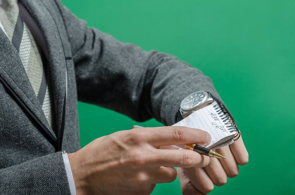 zakenman controleert de tijd op record in een notitieblok - Foto, afbeelding