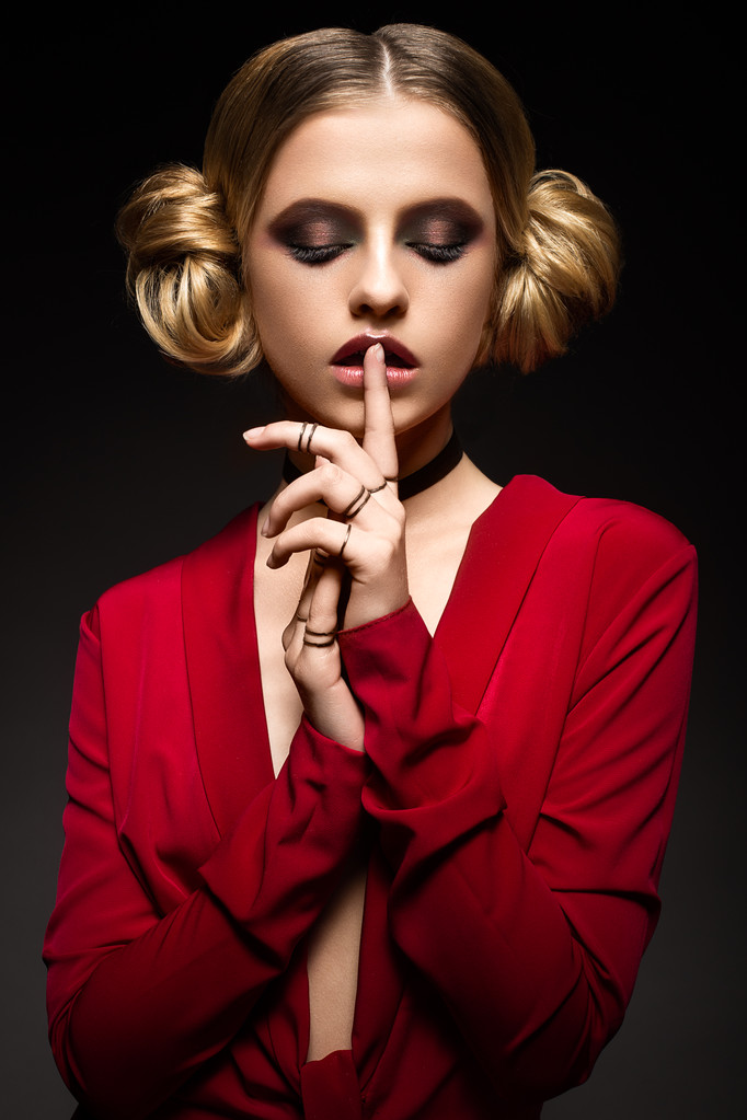 Bella ragazza in un abito rosso con una scollatura profonda e anelli neri sulle dita. Il modello con trucco luminoso
. - Foto, immagini