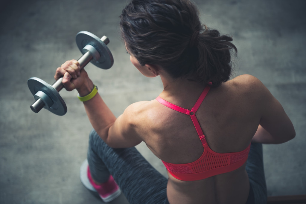 Vista superior del entrenamiento de mujer fitness con mancuerna en el gimnasio loft
 - Foto, Imagen
